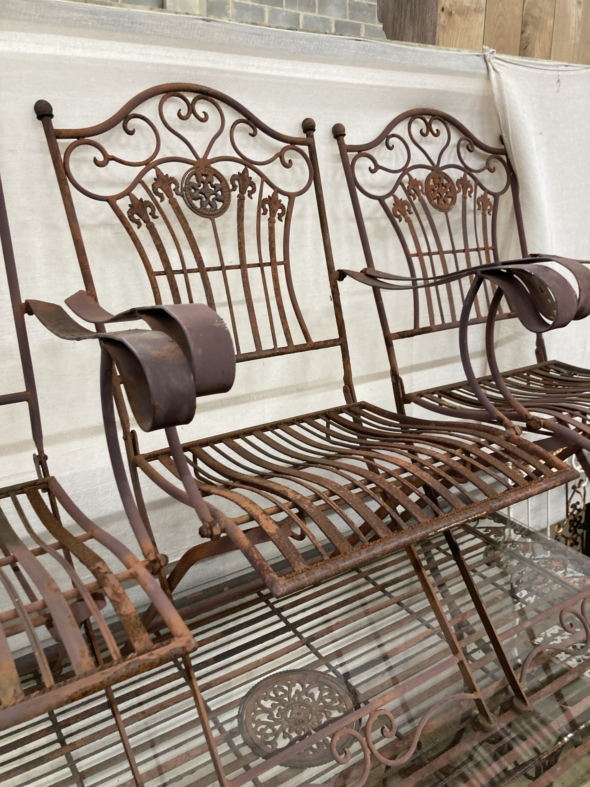 A wrought iron garden table, width 160cm, depth 80cm, height 76cm and six folding chairs